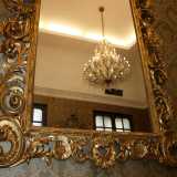 Uno dei lampadari riflesso in uno specchio anch'esso dorato
